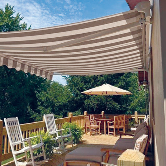Outdoor deck with striped retractable awning, chairs, and table under a clear blue sky.