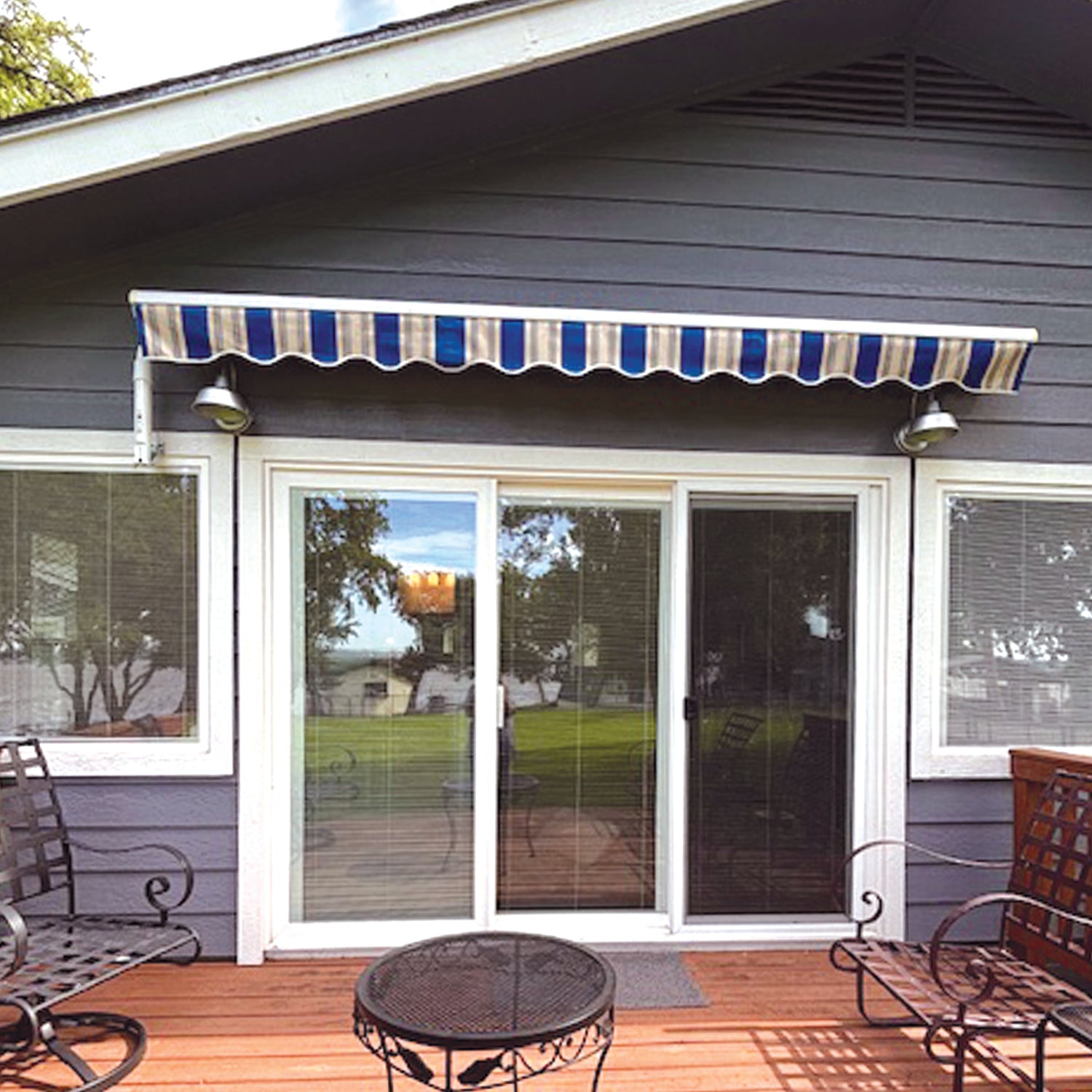 Blue and white striped awning over a sliding glass door with patio furniture below.
