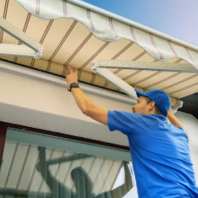 Person adjusting an awning on a building