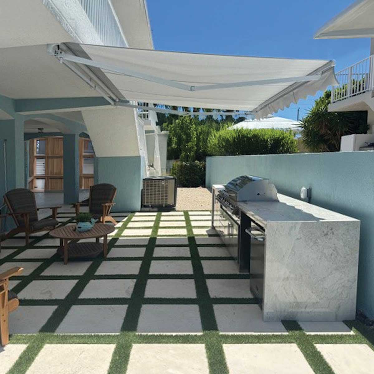 Outdoor patio area with a grill station, lounge chairs, and a pergola.
