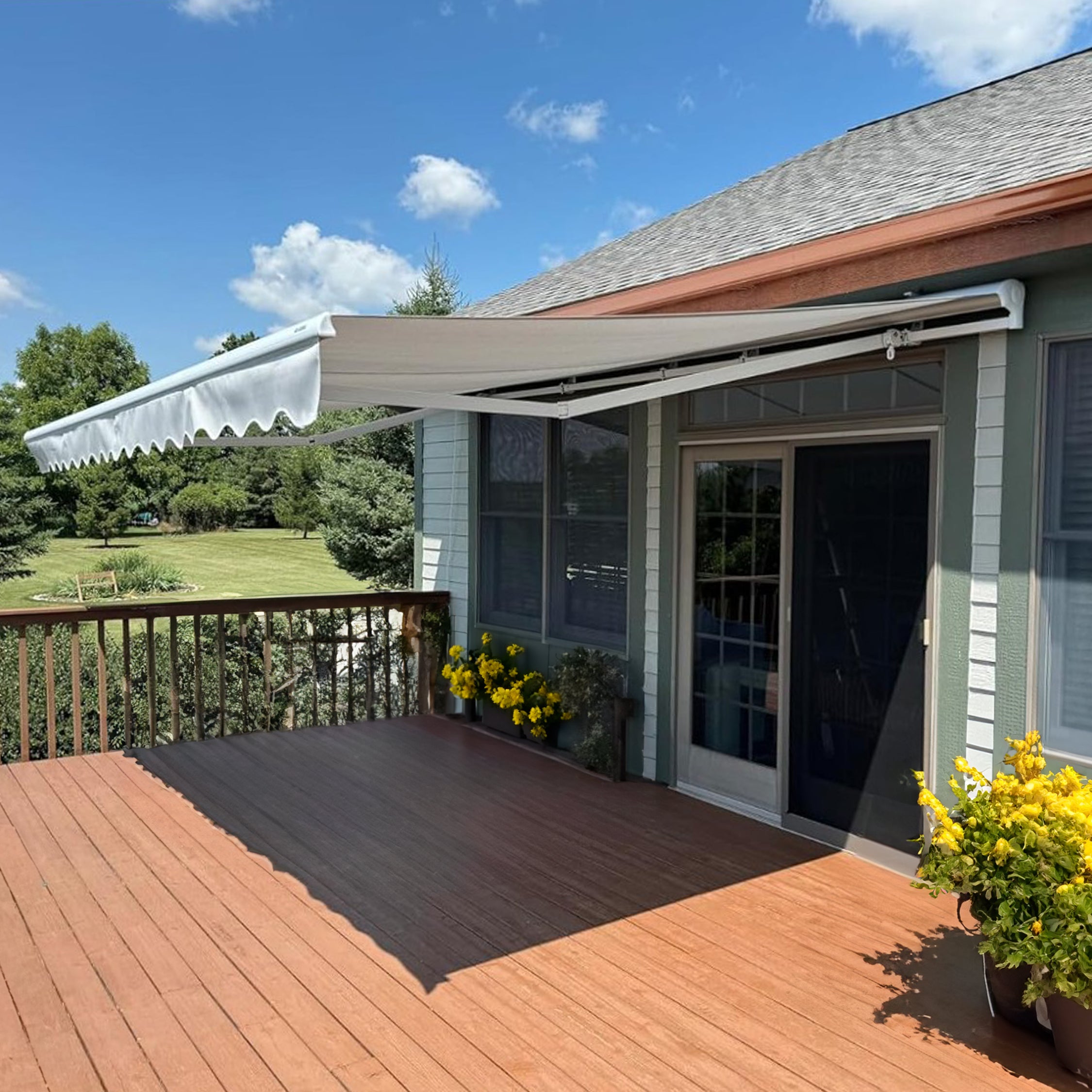 Outdoor deck with R112 retractable awning, potted plants, and a clear blue sky.