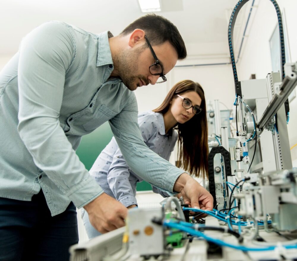 Two people working on a piece of industrial equipment in a laboratory setting.