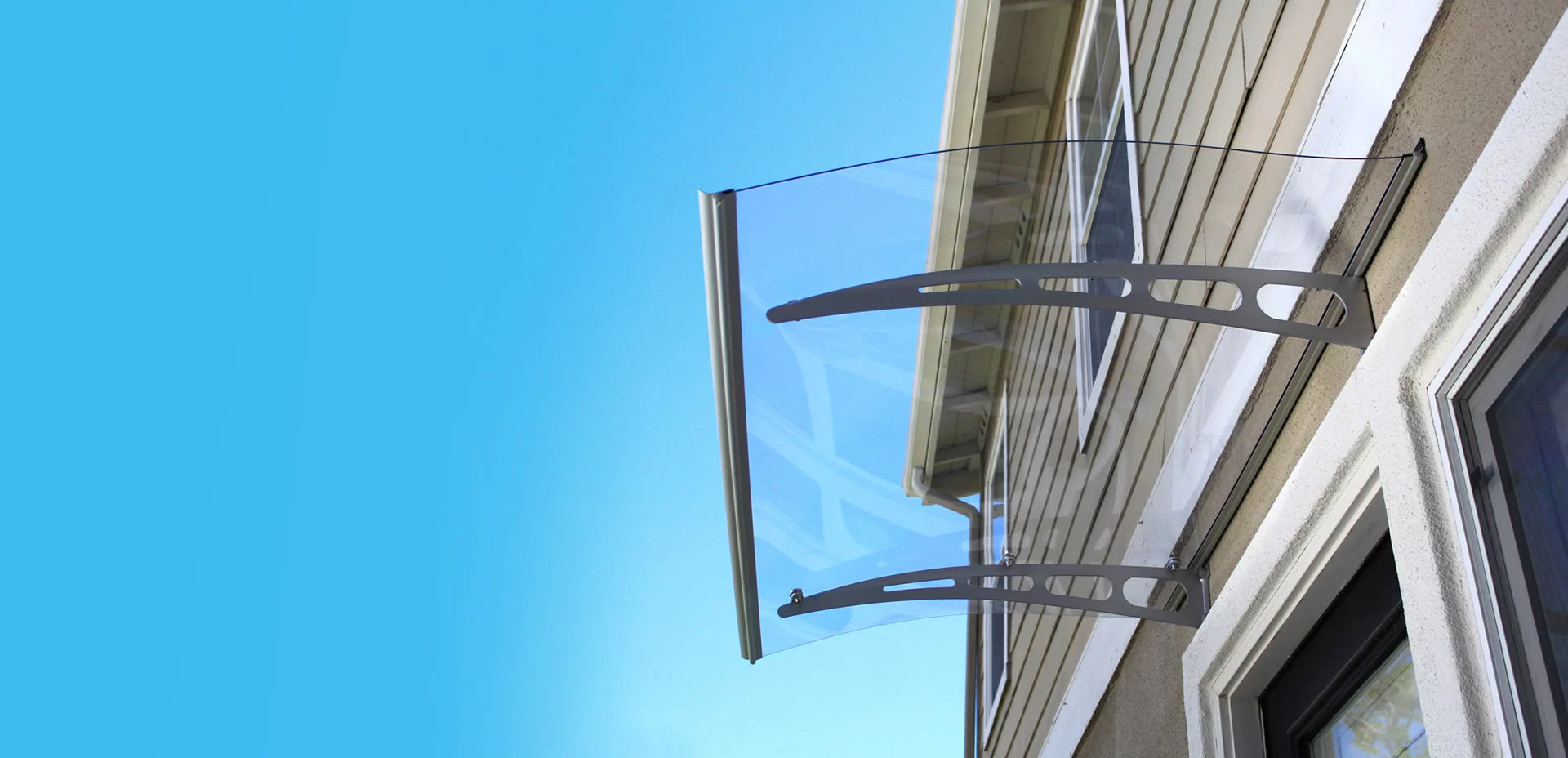 Glass canopy attached to a building with a clear blue sky background
