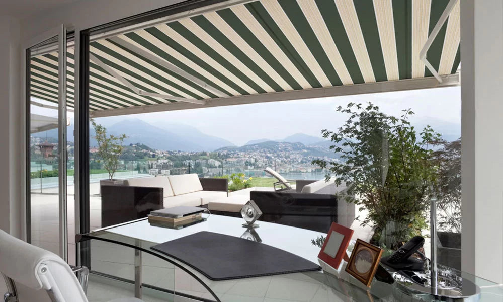 Outdoor patio with striped retractable awning, furniture, and scenic view.